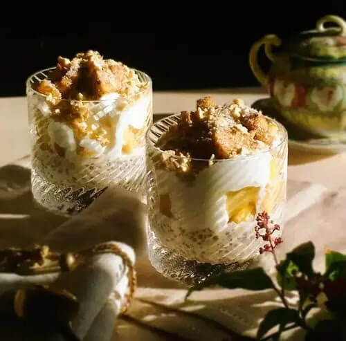 Due Super Colazioni in bicchieri di vetro su un tavolino con un tovagliolo e un rametto fiorito.